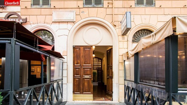 Un bâtiment doté d’une porte d’entrée centrale en arc de cercle, d’une enseigne au-dessus et d’une rambarde métallique sur le côté gauche.