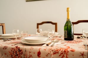 A dining table set with plates, glasses, and a bottle of champagne.