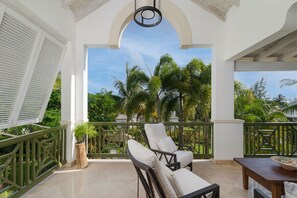 A balcony with a view of palm trees, a chair, and a table. - New and Modern Villa with Private Pool - Sugar Cane Ridge 3 (Westmoreland)