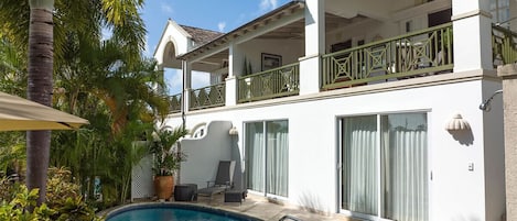Un bâtiment à deux étages doté d’une piscine, d’un espace extérieur aménagé et d’un balcon avec des rampes vertes.