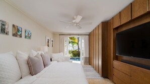 Ein Hotelzimmer mit einem großen Bett, einem Fernseher, Holzschränken und Blick auf einen Pool.