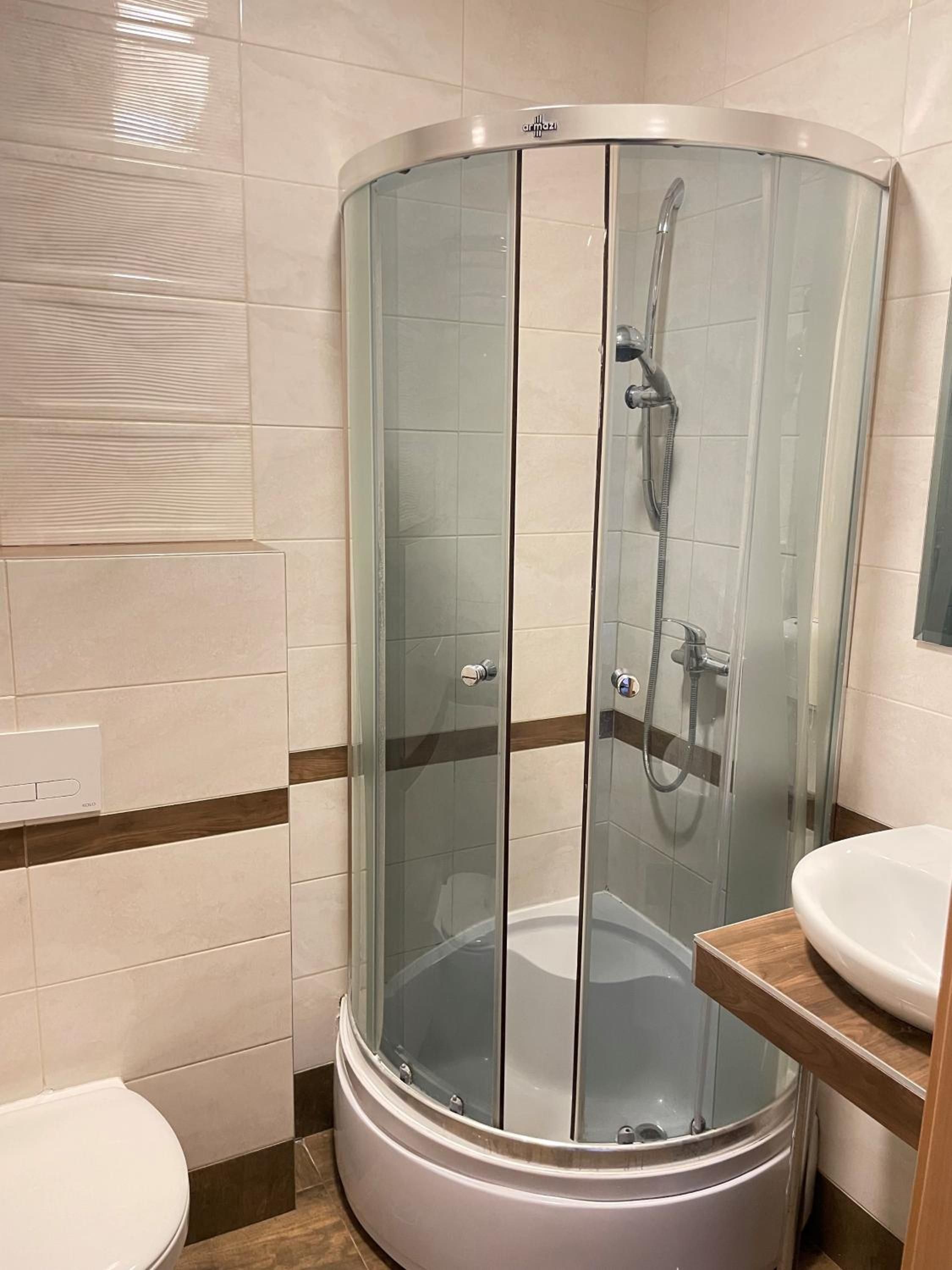 Un baño con ducha de vidrio, inodoro y lavamanos.