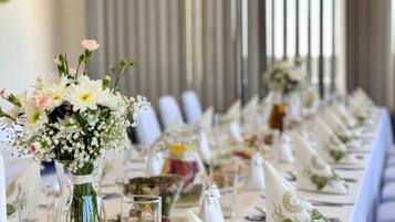 A long dining table set with white tablecloths, glassware, and floral centerpieces.