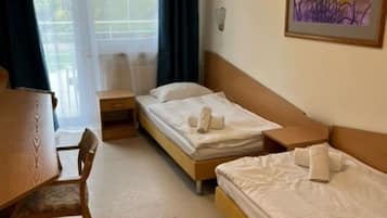 A hotel room with two single beds, a wooden desk, and a chair.