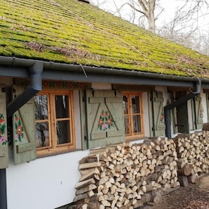 A traditional building with a moss-covered roof and wooden windows with floral decorations. - Geovita Jadwisin (Serock)