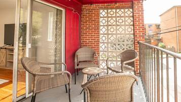 A balcony with wicker chairs and a glass door leading to an interior space.