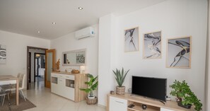 A modern living room with a TV, wooden cabinet, and artwork on the wall.
