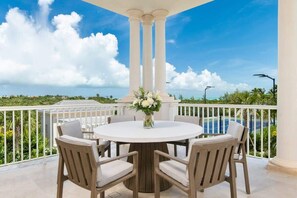 A round table with six chairs, a vase of flowers, and a view of a pool and greenery. - Villa Shambhala 3 BR (Long Bay)