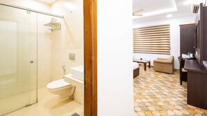 A bathroom with a glass shower door, a toilet, and a sink. - Hotel Panickers Residency (New Delhi)