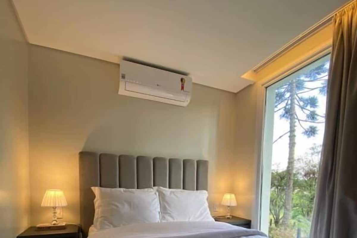 A neatly made bed with white linens and towels, a headboard, and two bedside lamps.