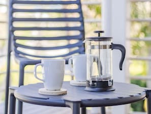 En kaffepress av fransk modell står på ett bord tillsammans med två vita kaffekoppar.