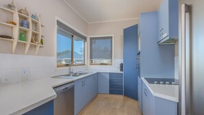 Eine moderne Küche mit weißen Arbeitsplatten, blauen Schränken und einem eingebauten Geschirrspüler.
