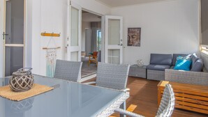 Ein modernes Wohnzimmer mit einem Glastisch, Korbstühlen, einem grauen Sofa und einer Holzbank.