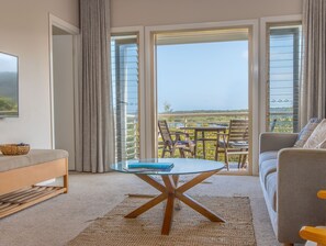 Ett modernt vardagsrum med ett soffbord med glasskiva, en soffa och en matplats med stolar.