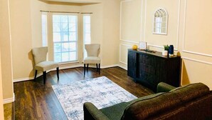 A living room with two chairs, a sofa, a dark wooden cabinet, and a large rug. - Spacious 6-bedroom house with pool and hot tub and theater room next to stadium! (Grand Prairie)