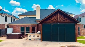 A residential house with a garage, a hot tub, and a patio area. - Spacious 6-bedroom house with pool and hot tub and theater room next to stadium! (Grand Prairie)