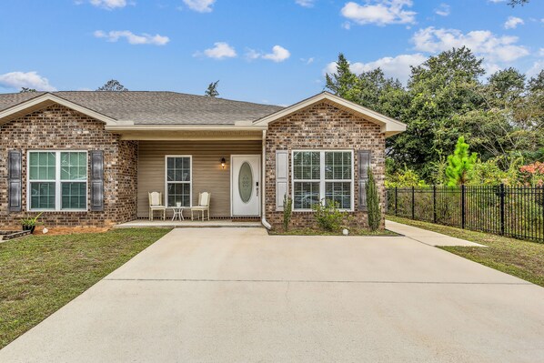 A two-story brick house with a front porch, a garage, and a well-maintained lawn.