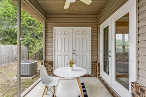 A covered patio with a white door, a brick wall, and a small table with chairs.