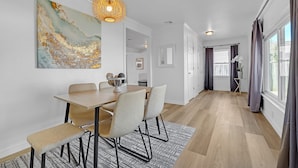 A modern dining area with a wooden table, four chairs, and a textured rug. - Charming Midtown Tulsa Home Steps From Expo Square.  (Tulsa)
