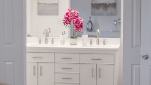 A modern bathroom with a double sink vanity, a mirror, and a decorative vase with pink flowers. - Charming Midtown Tulsa Home Steps From Expo Square.  (Tulsa)