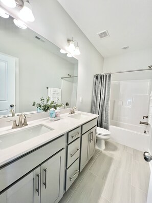 Bathroom features a dual sink vanity, large mirror, and shower area.