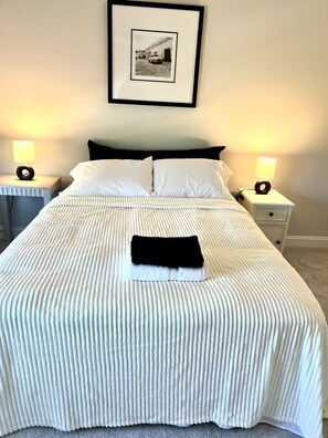 Restful retreat with a large bed, bedside tables, and a framed photograph.
