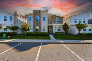A modern multi-story residential building with a stone facade, multiple windows, and a well-maintained lawn. - Epic Themed Game Room & Theater Near Disney Parks (Kissimmee)