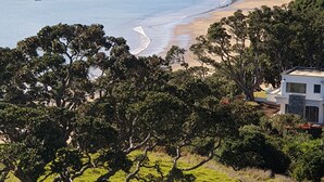 Eine Küstenlandschaft mit Strand, Bäumen und einem modernen Gebäude.