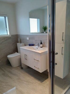 Un baño moderno con un tocador blanco, un inodoro y una cabina de ducha de vidrio.