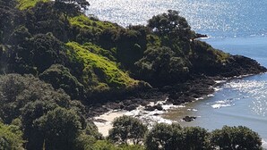 Eine Küstenlandschaft mit felsigen Ufern, dichtem Grün und freiem Blick auf das Meer.