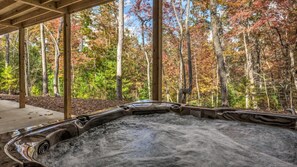 Ein Whirlpool in einer überdachten Anlage mit Blick auf einen Wald.