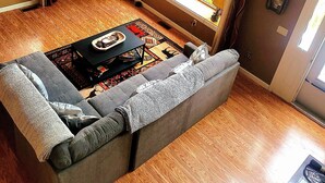 A cozy living room with a sofa, a coffee table, and a large window offering a view of trees.