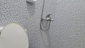 Un baño con inodoro, ducha y un cubo azul.