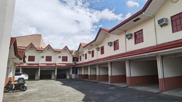 Un edificio con varias plazas de estacionamiento y una zona cubierta.