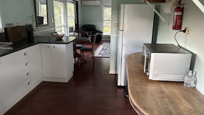 Cucina con mobili bianchi, un piano di lavoro in legno, un forno a microonde e un frigorifero. C'è un'area pranzo con tavolo e sedie, e un tappeto sul pavimento.