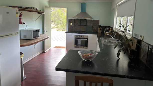 Una cucina con forno a microonde, forno e lavello. Una finestra offre vista su alberi.