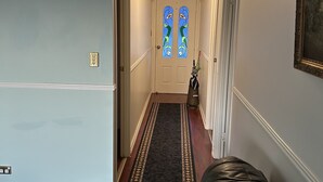 Un corridoio con un divano in pelle nera, un tappeto decorato e una porta con vetrate artistiche.