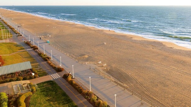 A coastal walkway with a beach, a covered seating area, and a view of the sea. - Coastal Catch: Walk to Boardwalk (Virginia Beach)