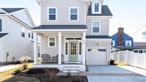 A two-story house with a front porch, a garage, and a well-maintained lawn. - Coastal Catch: Walk to Boardwalk (Virginia Beach)