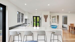 Una cocina moderna con una isla central, taburetes de bar y vistas al exterior.