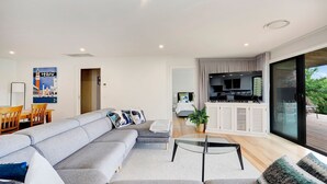 Una sala de estar moderna con un sofá seccional gris, una mesa de centro de vidrio y un televisor montado en un mueble blanco.