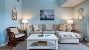 A living room with a light blue wall, a white sofa, a white coffee table, and two lamps. - 2 BR/2BA Courtside Villa! Amenity access NOT available Dog Friendly!Tennis Court Views! (Seabrook Island)