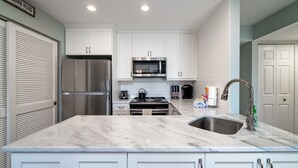 A modern kitchen with white cabinetry, a stainless steel refrigerator, a microwave, and a sink with a faucet. - 2 BR/2BA Courtside Villa! Amenity access NOT available Dog Friendly!Tennis Court Views! (Seabrook Island)