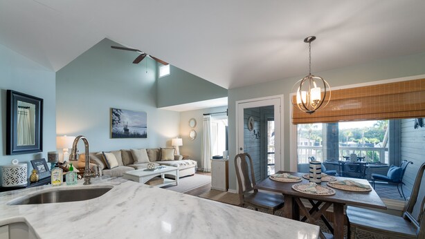 A modern kitchen with a marble countertop, a dining area with a wooden table and chairs, and a cozy seating area with a sofa and a coffee table. - 2 BR/2BA Courtside Villa! Amenity access NOT available Dog Friendly!Tennis Court Views! (Seabrook Island)