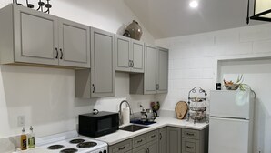 Una cocina moderna con gabinetes grises, una estufa blanca, un lavamanos y un refrigerador.