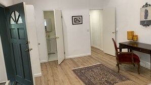 Una habitación con piso de madera, una mesa de comedor con sillas, un tapete y una puerta que da a un baño.