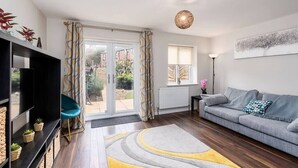 A modern living room with a grey sofa, a blue chair, a black entertainment unit, and a yellow rug. - Stunning 3 Bedroom Home Hillsborough Sheffield (Hillsborough)