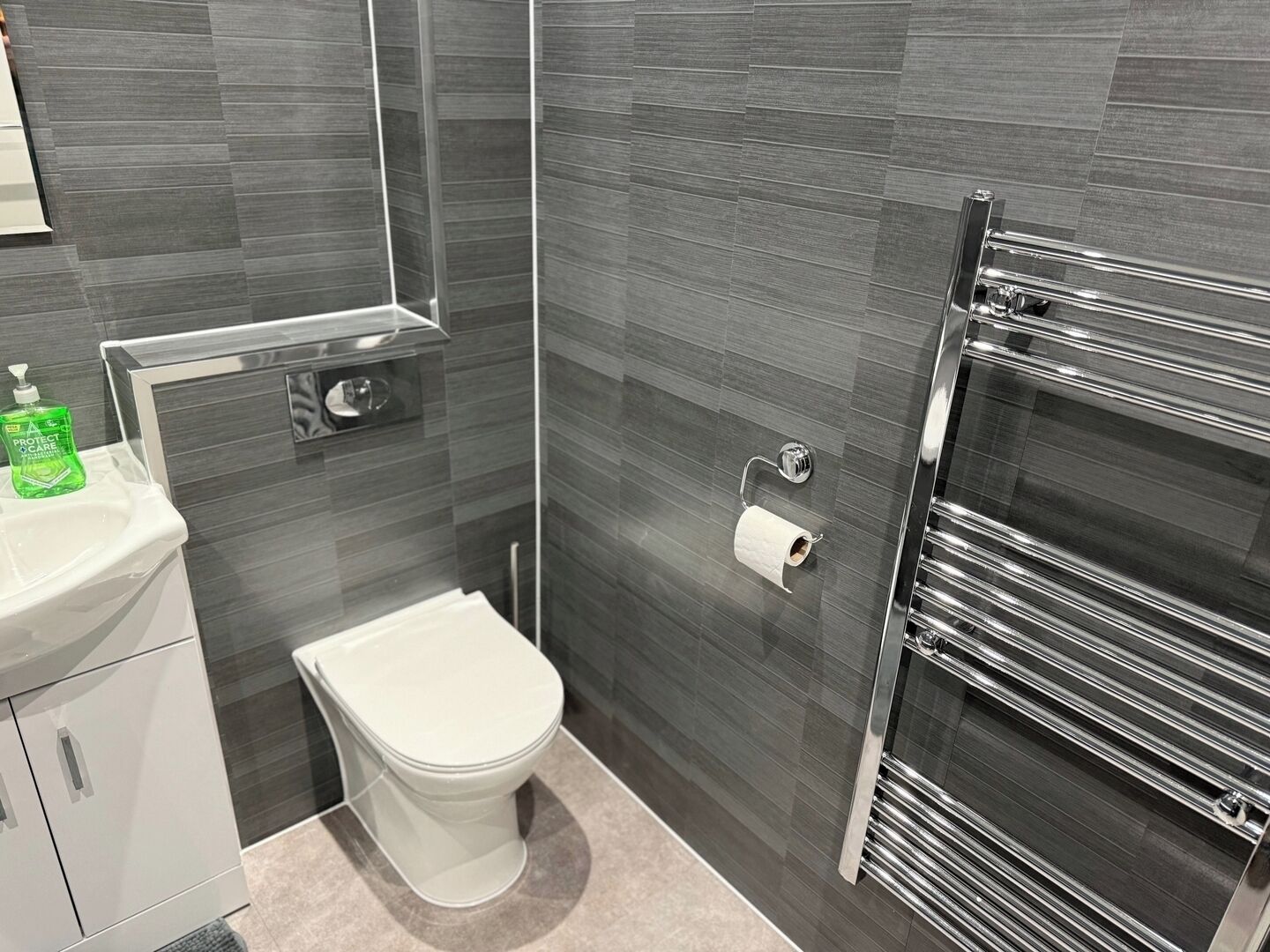 A modern bathroom with a toilet, sink, and towel rack.