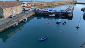 A harbor with boats docked, a building with a red roof, and a calm sea in the background. - Superb One Bedroom Getaway in Dysart Kirkcaldy (Dysart)