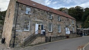 A stone building with a red-tiled roof, a staircase leading to the entrance, and a sign indicating it is a pub. - Superb One Bedroom Getaway in Dysart Kirkcaldy (Dysart)